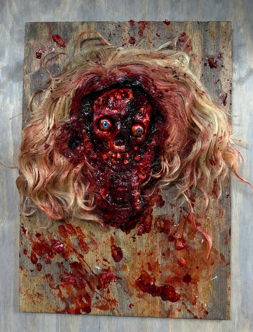 Front view of the handmade Bludgeoned Smashed Face horror prop on plywood